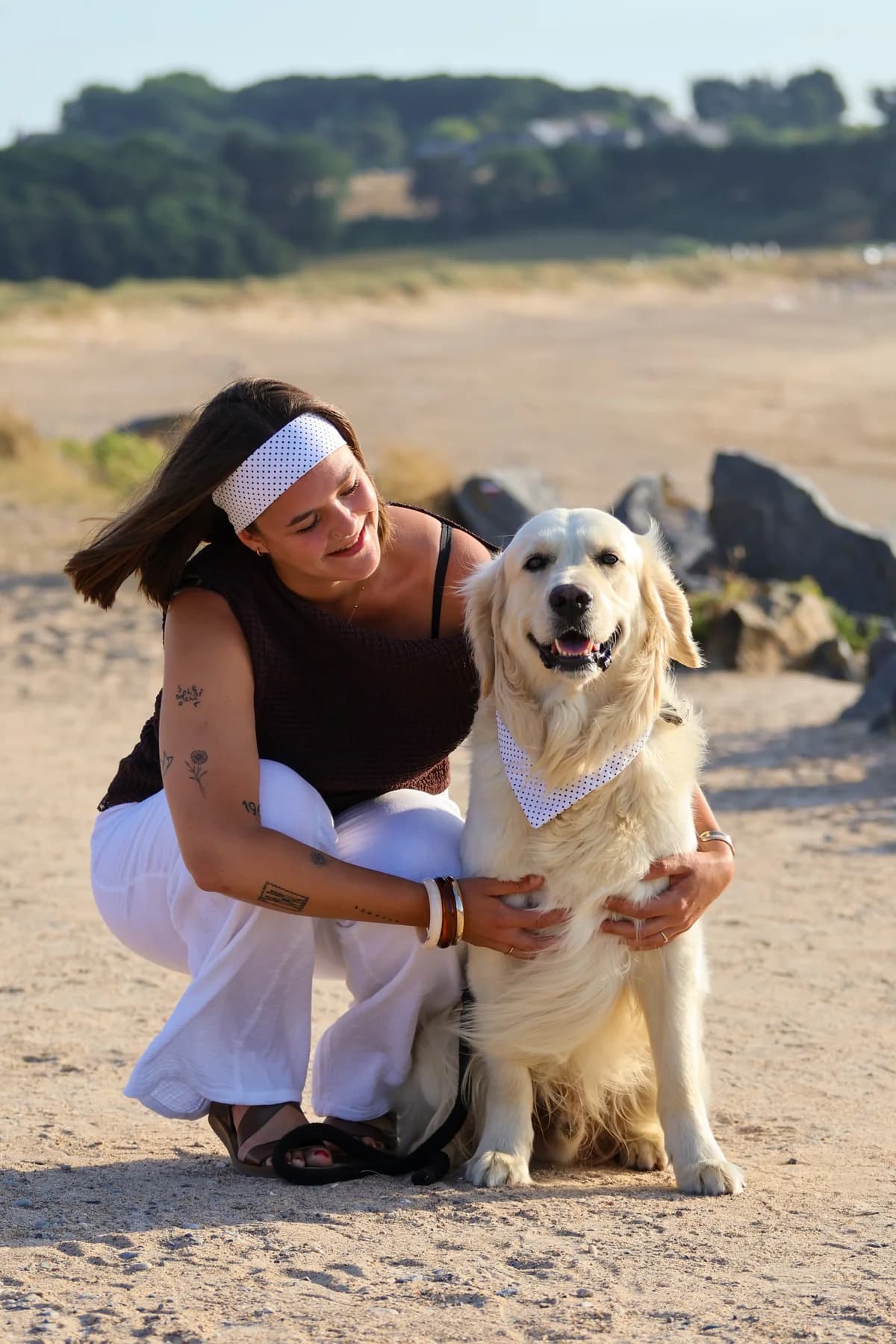 Femme accroupie avec un golden retriever sur la plage